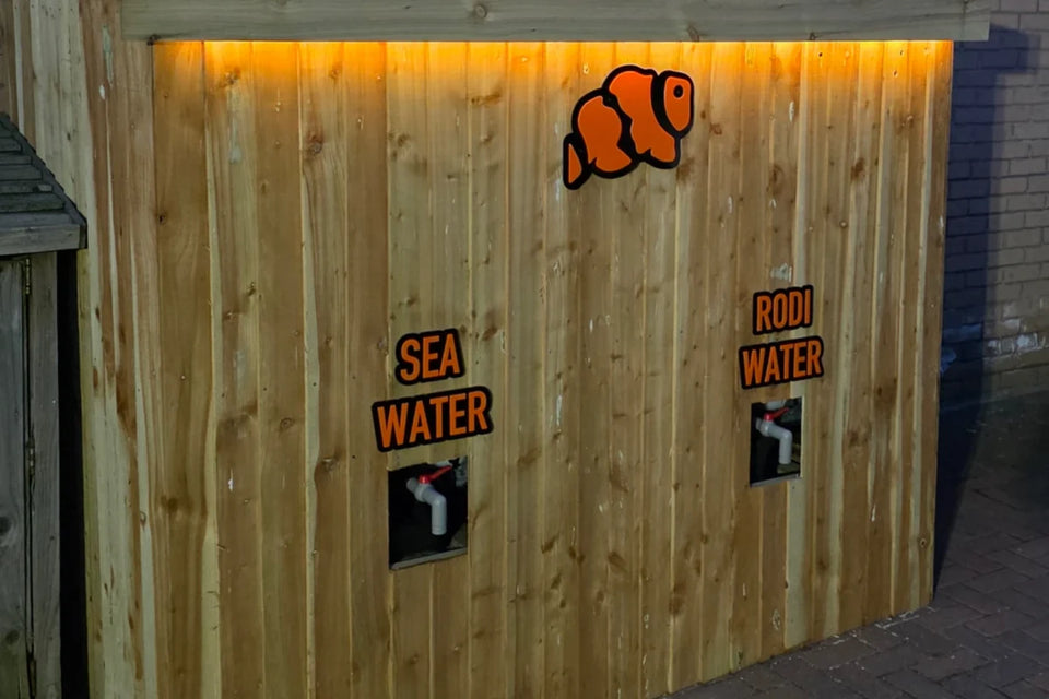 Wooden water station with sea water and RODI water taps and an orange clownfish plaque lit from above