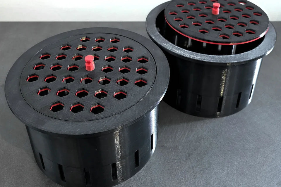 Two large black 3D printed filter cups, 1 with its hexagon pattern lid fitted